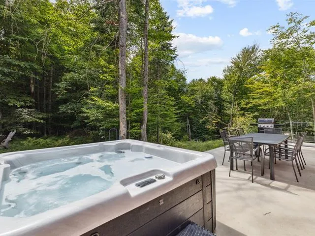 Outdoor hot tub on terrace with forest views and BBQ area